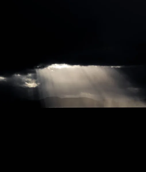 Dark clouds over the coastline and ocean with ray lights — Stock Photo, Image