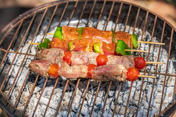 Preparing meat brochettes with vegetables over grill — Stock Photo, Image