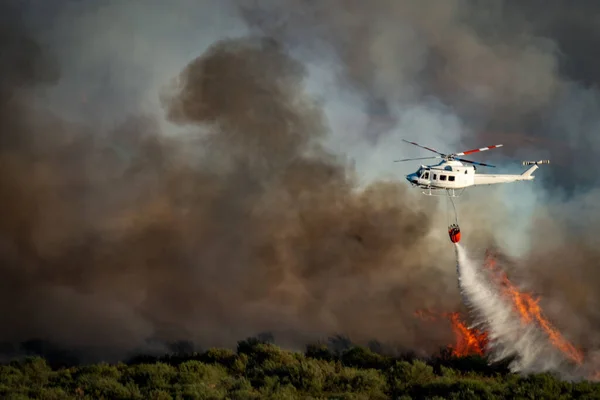 Rook en enorme brand en wazig helikopter met bambi emmer dumpen water — Stockfoto