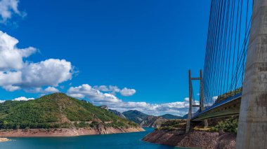 Mavi gökyüzü üzerindeki asma köprü ve baraj