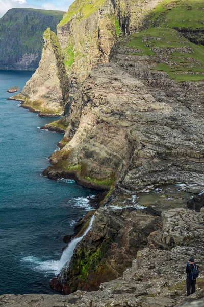 Onherkenbare toerist observeert de ruwe kustlijn van het eiland — Stockfoto