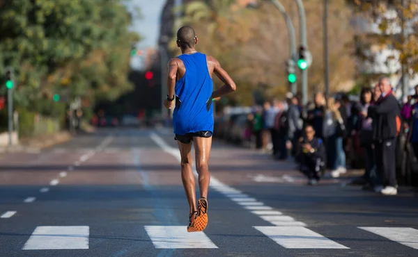 Biegacz maratoński widok z tyłu przelatujący nad drogą — Zdjęcie stockowe