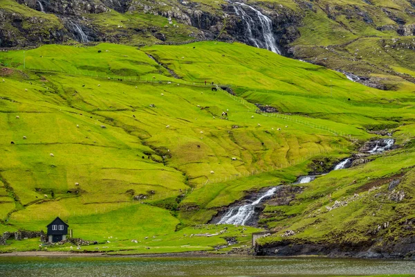 Waterfall, lake and house under the hill — Stock Photo, Image