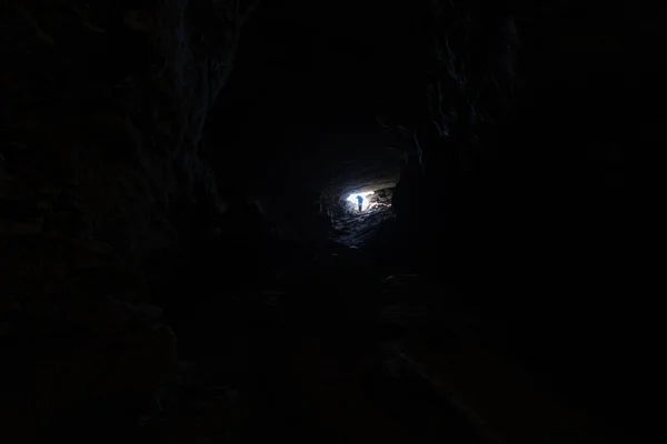 Rear view of unrecognizable person leaving the cave — Stock Photo, Image