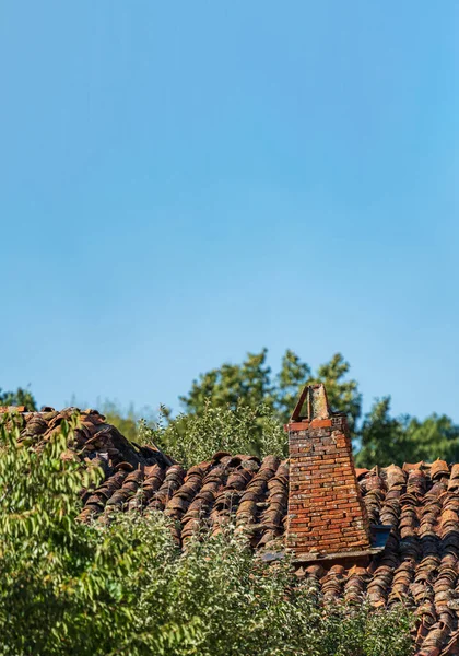 Vintage chimney over tile roof crooked under blue sky — Stock Photo, Image