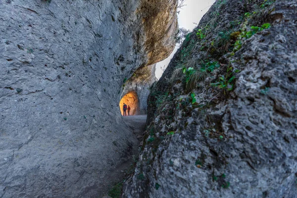 Dos personas irreconocibles caminando a través del túnel de las rocas —  Fotos de Stock