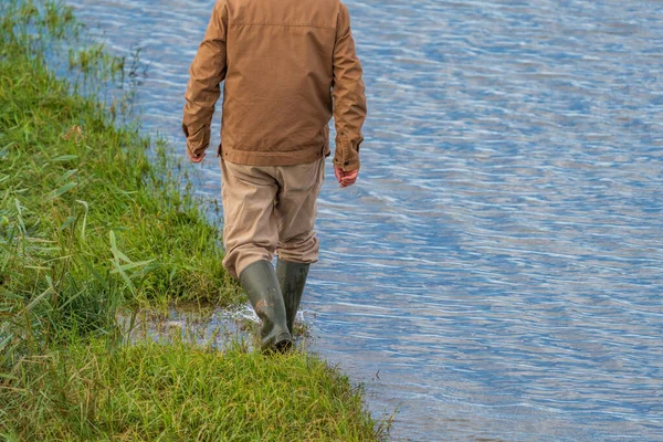 Personne méconnaissable marchant près d'un bord de route inondé — Photo