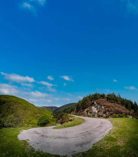 Steep high slope u-shape mountain road under blue sky — Stock Photo, Image