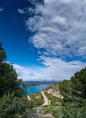 Bulutların altındaki baraja giden kıvrımlı yolda
