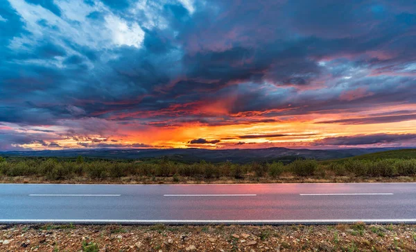 Rosso intenso tramonto nuvoloso e strada diritta — Foto Stock