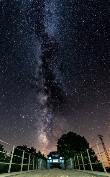 Night shot of 4x4 car and narrow bridge under the milky way — Stock Photo, Image