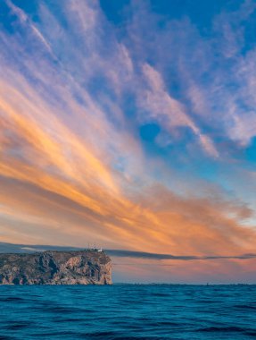 Deniz feneri ve tekneler okyanusta bulutların altında