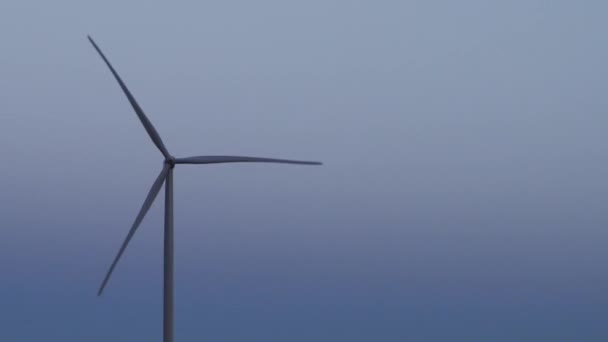 Single modern windmill rotating against dusk, loopable — Stockvideo