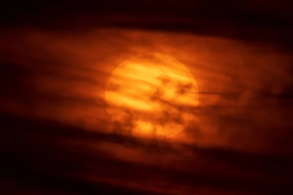 Huge sun at orange sunset covered by clouds — Stock Photo, Image
