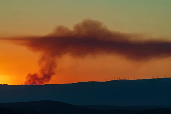 Ogień dymu nad wzgórzami pokryty wiatrakami — Zdjęcie stockowe