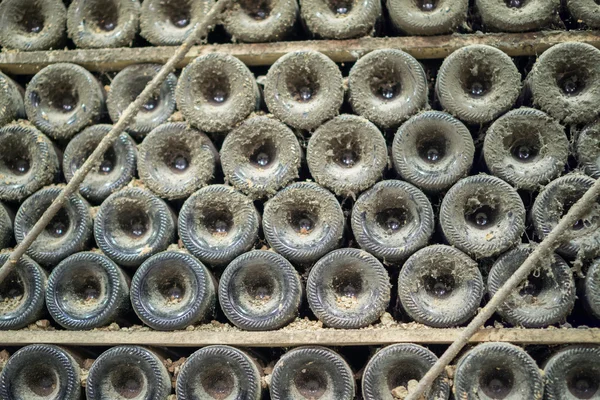 Fondo de botellas cubiertas de polvo viejo en bodega, profundidad de campo poco profunda, vista frontal — Foto de Stock