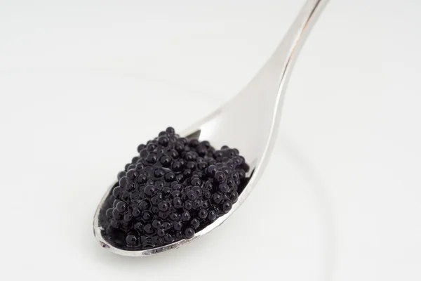 Caviar em uma colher sobre placa branca — Fotografia de Stock