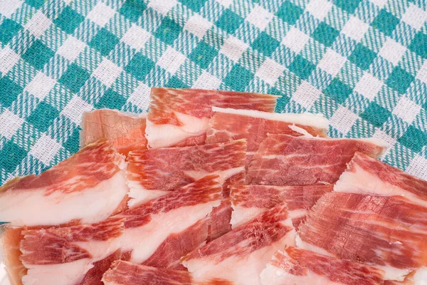 Vista superior de rebanadas de jamón serrano sobre plato y mantel — Foto de Stock