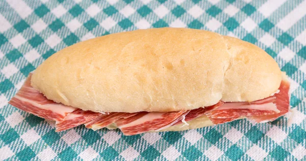 Side view of Serrano ham sandwich over checkered tablecloth — Stock Photo, Image