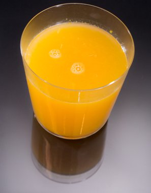 Portakal suyunun en üst görüntüsü siyah ve cam yansımasının üstünde.