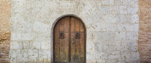 Stare drewniane drzwi i ściany kamienne — Zdjęcie stockowe