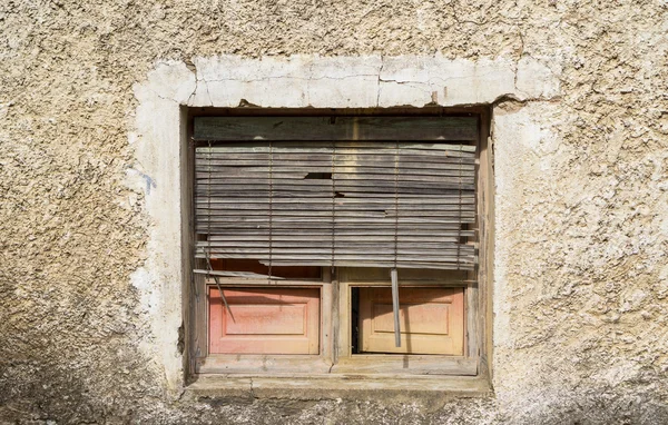 Danneggiato Vecchia finestra con telaio in legno, muro di pietra e cieco rotto — Foto Stock