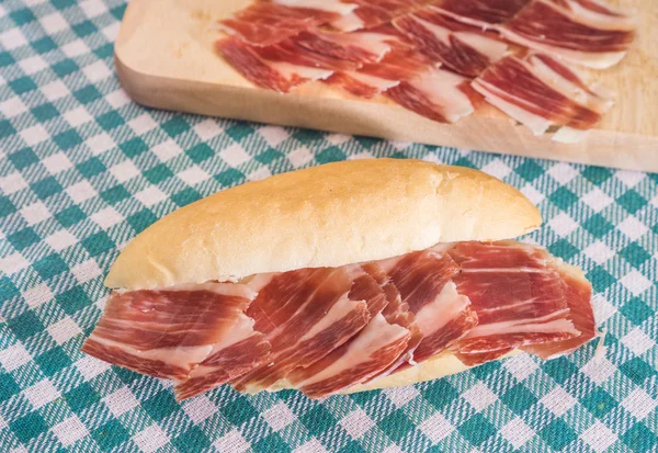 Serrano ham sandwich over checkered tablecloth — Stock Photo, Image