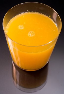 Portakal suyunun en üst görüntüsü siyah ve cam yansımasının üstünde.