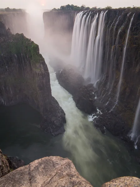 维多利亚瀑布日落从赞比亚的一面，在前台的岩石 — 图库照片