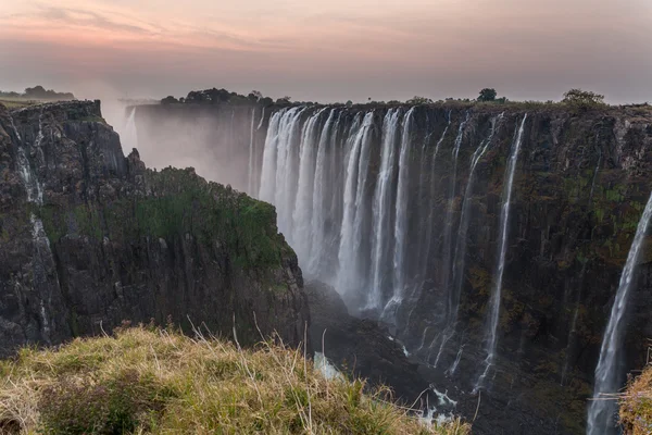 Victoria Falls from Zambia side at dusk, rocks in the foreground — Stock Photo, Image