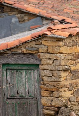 Yaşlanmış ahşap kapısı ve huzurlu bir kırsal alanda kurulmuş zamansız mimari detayları olan büyüleyici taştan bir ev..
