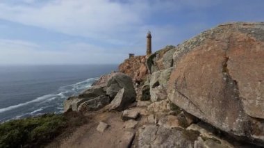 Galiçya 'nın Costa da Morte kentindeki dramatik bir Atlantik uçurumuna tünemiş bir deniz fenerinin görüntüsünü alan insansız hava aracı..