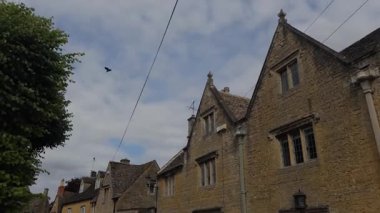 Büyüleyici taş evlerin ve ikonik Bourton-on-the-Water, Cotswolds, İngiltere 'deki manzaralı sokakların etrafında geziniyorum..