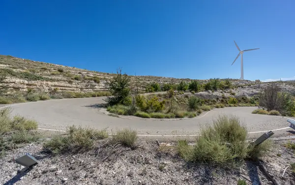 U-shape curved road and wind turbine against sun — Stock Photo, Image