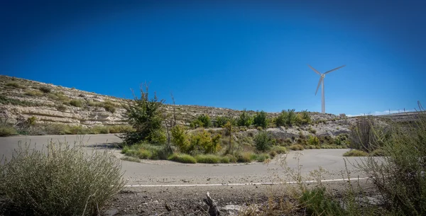 Carretera curva en forma de U y turbina eólica contra el sol —  Fotos de Stock