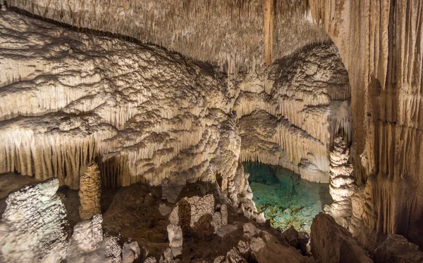 Cueva con lago en el fondo, estalactitas y estalagmitas — Foto de Stock