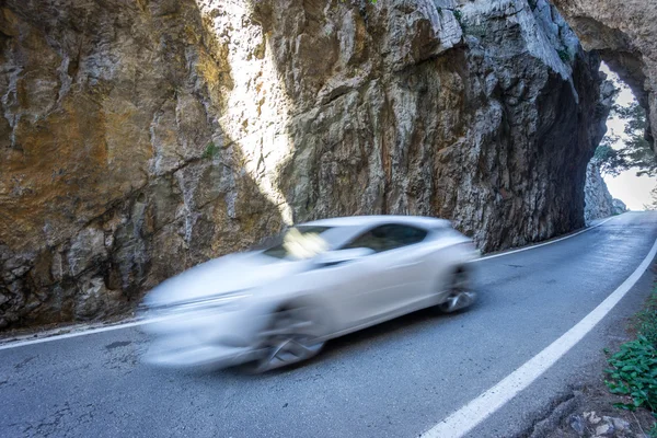 Route asphaltée entre les rochers avec voiture blanche floue — Photo
