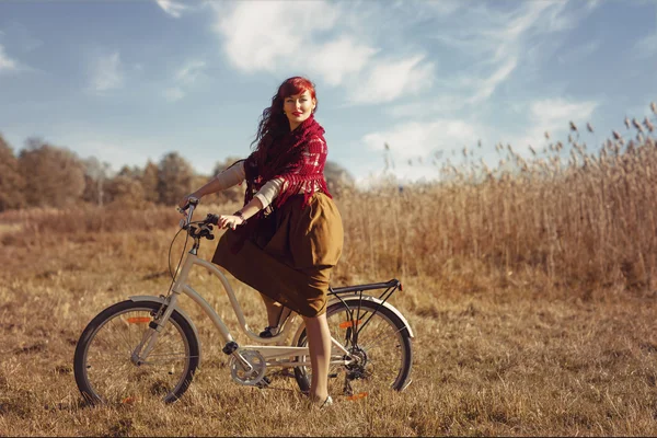 Pretty girl riding bicycle in field — Stock Photo, Image