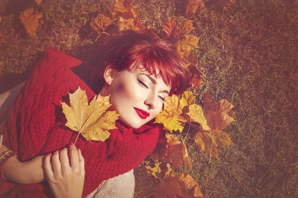 Zrzavé vlasy holka ležící s podzimní javorový list — Stock fotografie