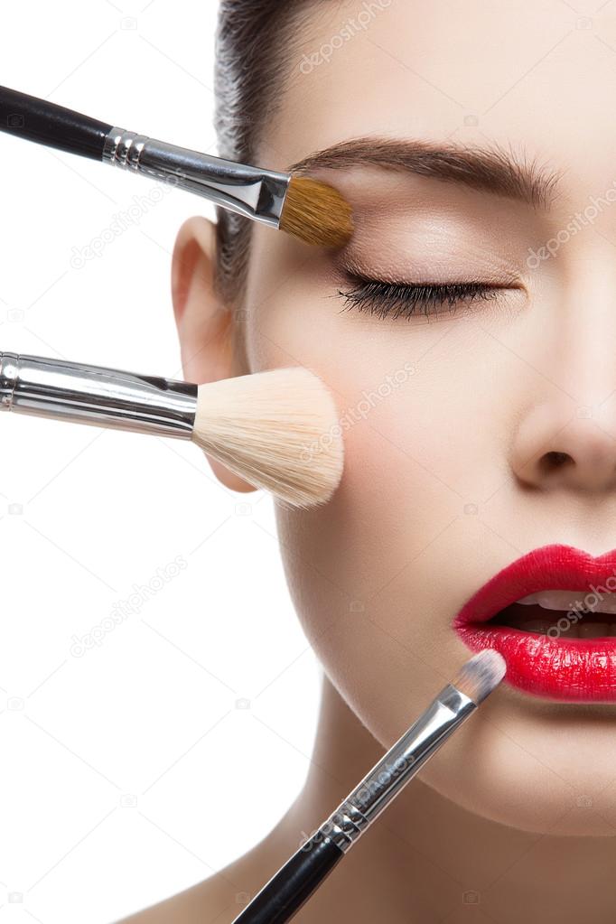 Beautiful girl with makeup brushes