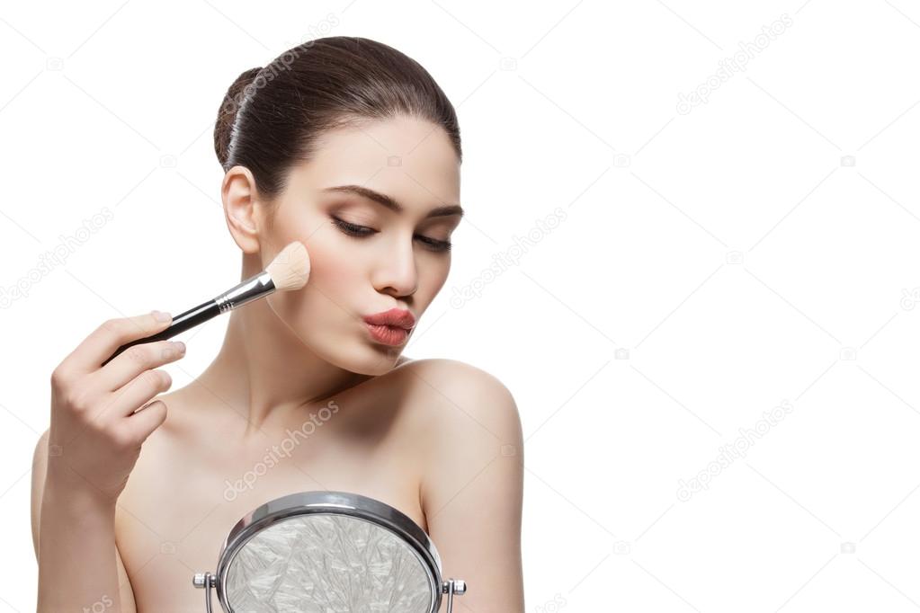 Beautiful girl applying blush with brush