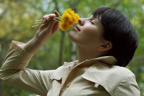 La bella donna sta annusando i fiori nel parco. — Foto Stock