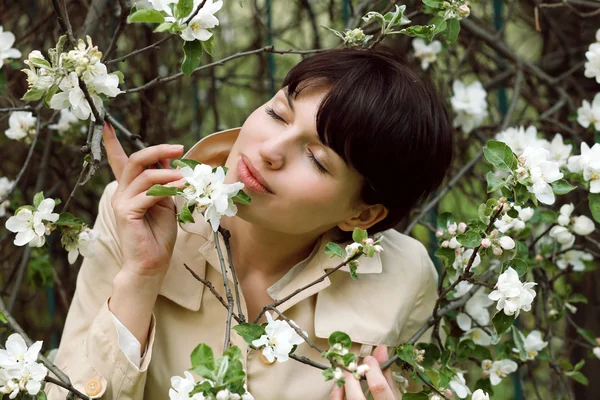 Mulher bonita está cheirando as flores no parque — Fotografia de Stock