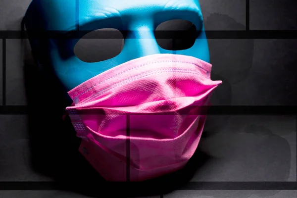 Medical pink mask put on a blue mask. black background