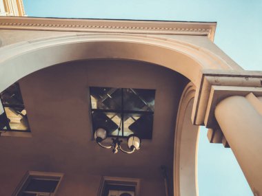 Gökyüzüne karşı sütunları olan bir binanın cephesi. Alttan üste resim.