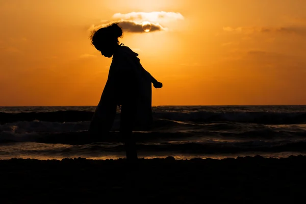 Silhouette de petite fille sur une plage au coucher du soleil — Photo