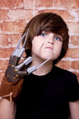Kid with scary nails on face. Brick wall background clipart