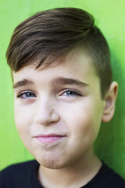 Close-up van portret van een knappe jongen glimlachen op groene achtergrond — Stockfoto