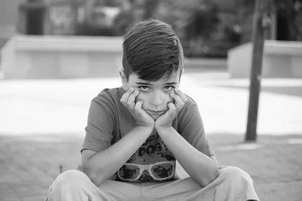 Bonito menino chateado choramingando no parque em um dia ensolarado — Fotografia de Stock