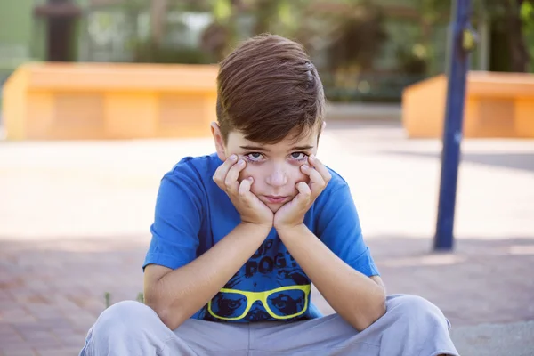 Schattige boos jongen steenbolk in het park op een zonnige dag — Stockfoto